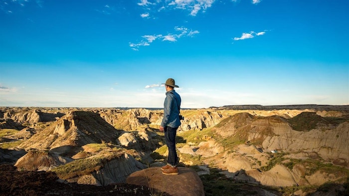 Une personne debout sur un promontoire rocheux observe des canyons qui s’étendent à perte de vue.