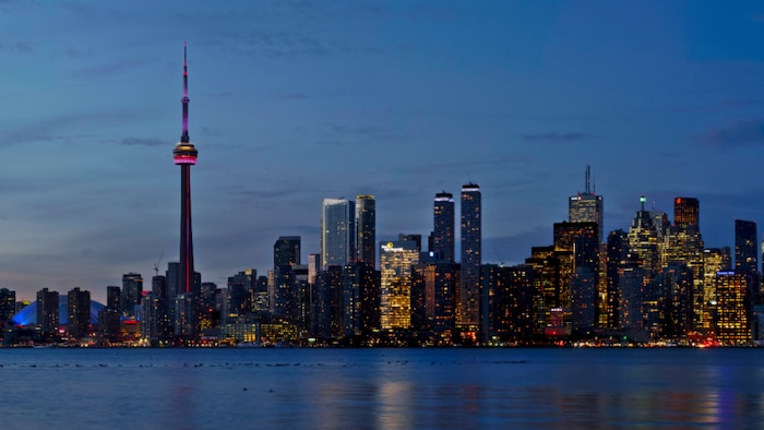 الصورة: وسط تورونتو عند الغسق في صورة مأخوذة من إحدى جزر تورونتو في بحيرة أونتاريو الكبرى، ويبدو في يسار الصورة برج "سي ان" (CN Tower)، أعلى بناء في العالم عند الانتهاء من تشييده عام 1976