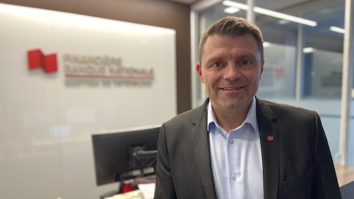 Bastien Poirier est devant une affiche de la Banque Nationale à l'intérieur.
