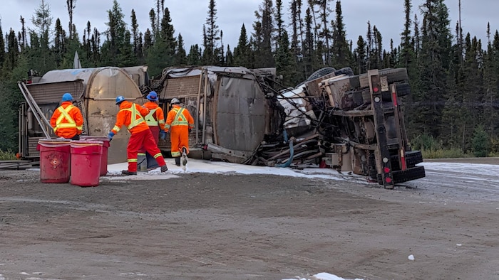 Un camion renversé sur une route de terres.