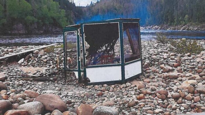 Un gazébo brûlé sur le bord d'une rivière.