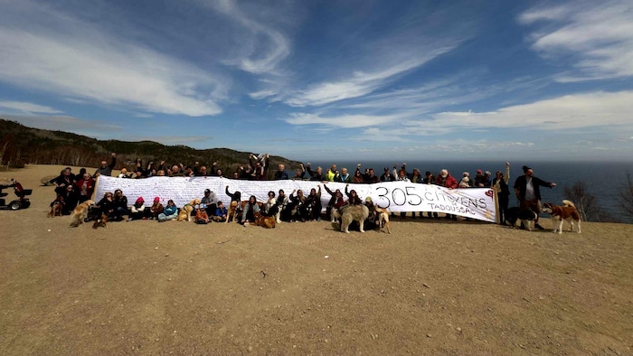 Des citoyens tiennent une longue banderole à l'extérieur sur des dunes.