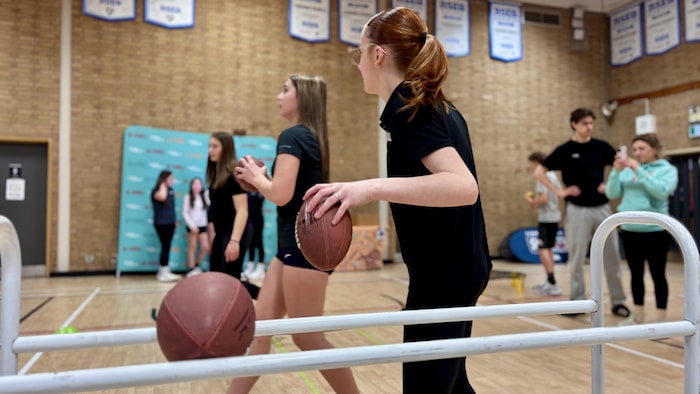 Students practicing football drills in a gymnasium