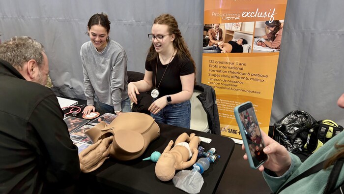 Des professionnels de l'éducation, devant un kiosque, présentent un programme scolaire.