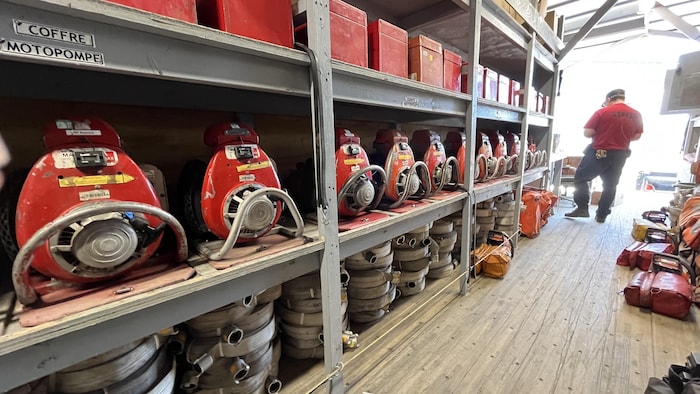Plusieurs outils pour les pompiers forestiers, dont des pompes, sont rangés dans un garage.