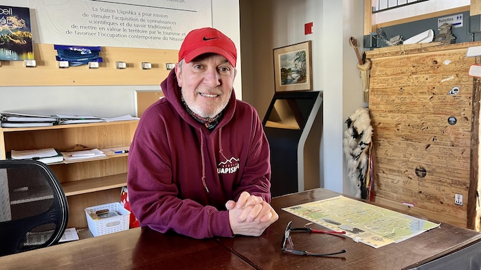 John Ferguson est devant un bureau à l'intérieur.