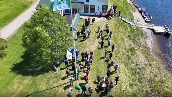 Un drapeau de la communauté et beaucoup de gens réunis autour dans une pourvoirie de la Côte-Nord.