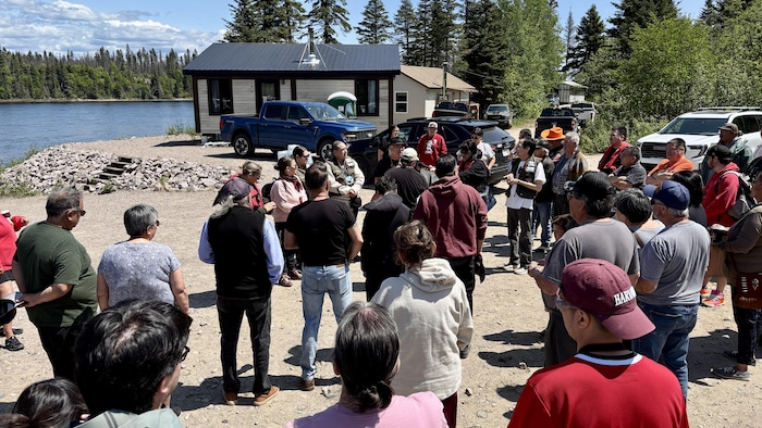 Des dizaines de gens sont réunis devant la berge d'une rivière.