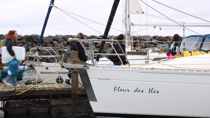 Des personnes marchant dans une marina vers un voilier.