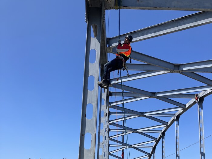 Un ingénieur est accroché à des cordes d'un pont.