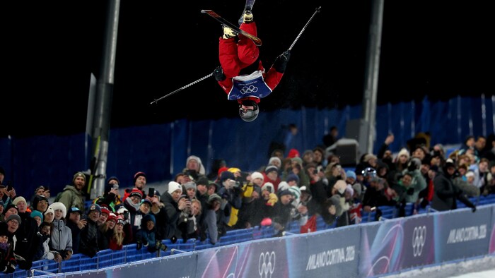 Un skieur acrobatique exécute un saut à la demi-lune.