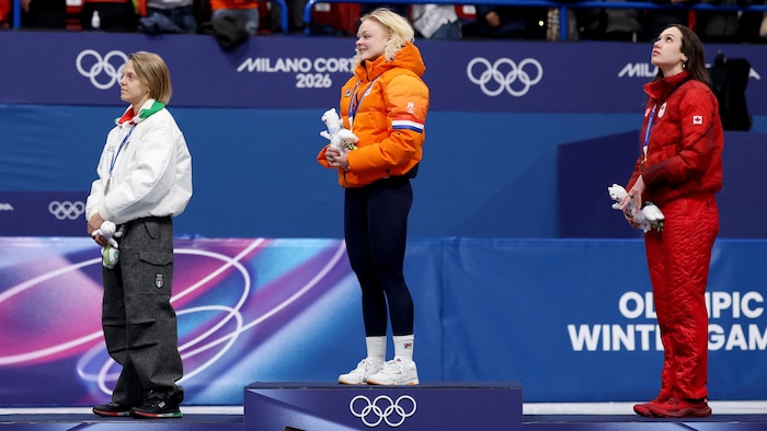 Trois femmes se tiennent debout sur le podium, chacune sur sa marche.