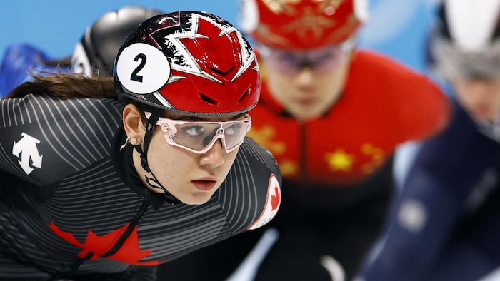 Plan rapproché d'une patineuse en action, coiffée d'un casque et de lunettes de protection.