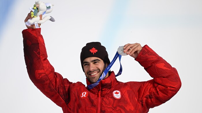 Éliot Grondin tient sa médaille d'argent dans une main et une peluche dans l'autre.