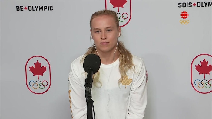 Ellie Black se pone delante del micrófono con los auriculares en los oídos para dar su entrevista.