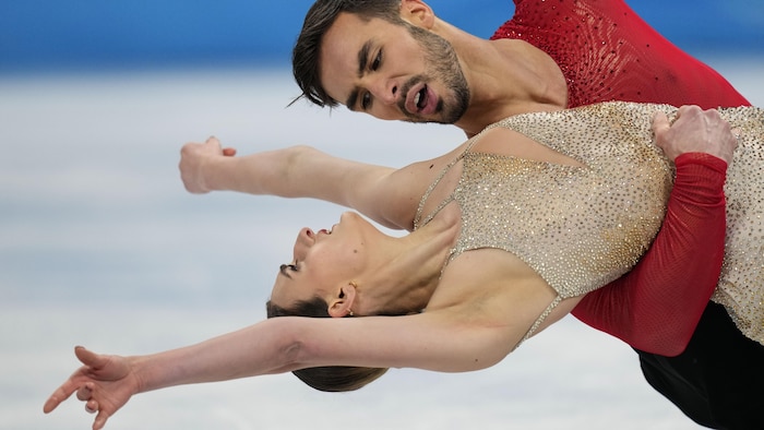 Il la tient par le dos.