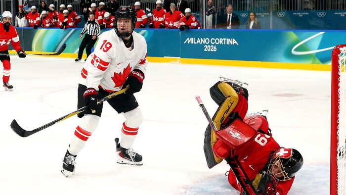 Une gardienne de but est couchée sur la glace alors qu'elle arrête une rondelle.