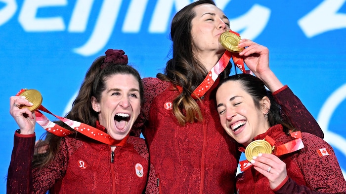 Ivanie Blondin, Valérie Maltais et Isabelle Weidemann montrent fièrement leur médaille d'or et fêtent sur le podium. 