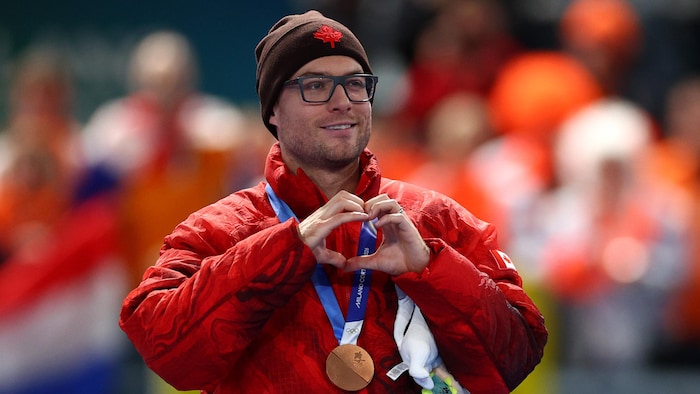 Le patineur de vitesse canadien Laurent Dubreuil, sa médaille de bronze au cou, un cœur formé avec ses mains et le sourire aux lèvres, après l'épreuve du 500 m sur longue piste.