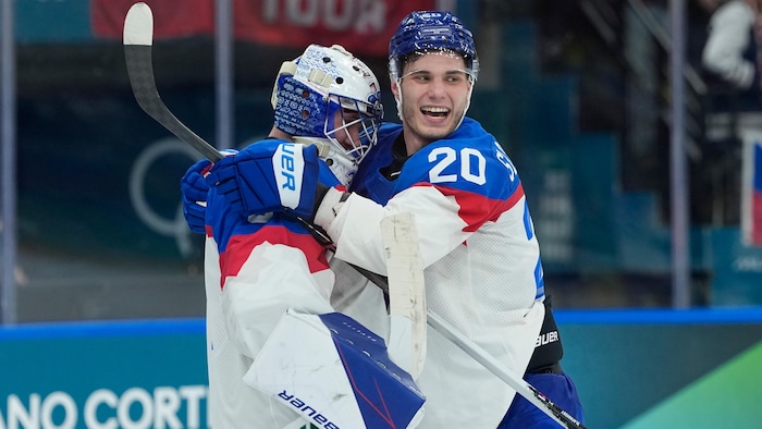 Un gardien et un hockeyeur s'enlacent et sourient après une victoire.