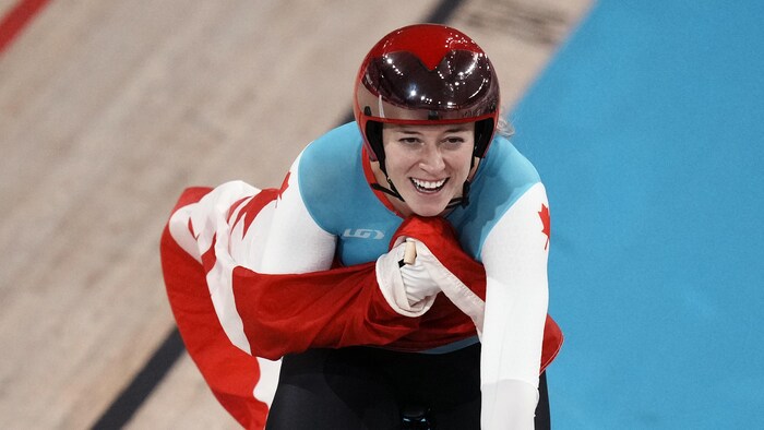Une cycliste sur son vélo sourit avec le drapeau canadien
