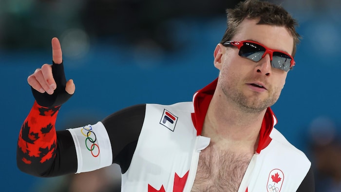 Laurent Dubreuil lève le bras et pointe vers le haut avec un doigt.