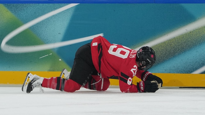 Une hockeyeuse tombe sur la patinoire.