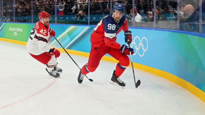 Martin Necas se dirige vers la rondelle pendant que Phillip Bruggisser le suit.