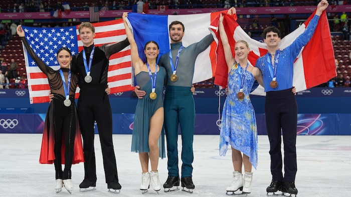 Les médaillés en danse sur glace tiennent le drapeau de leur pays derrière leur dos.