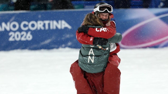 Une skieuse serre sa coéquipière contre elle et sourit.
