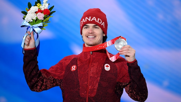 Le bosseur airs fièrement avec sa médaille d'argent dans sa main gauche et un bouquet dans l'autre.