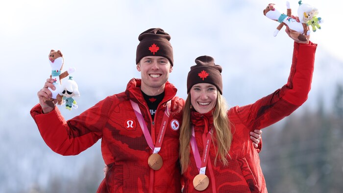 Deux personnes sourient sur le podium avec leurs médailles de bronze au cou.