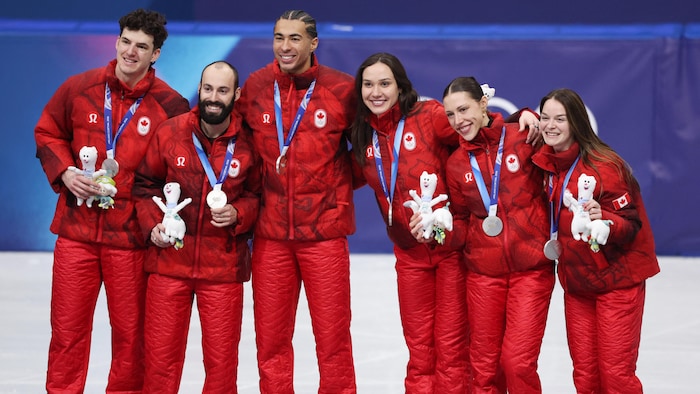 Médaille autour du cou, les patineurs sourient.