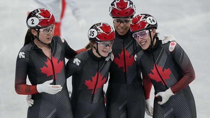Quatre patineuses se font une accolade.