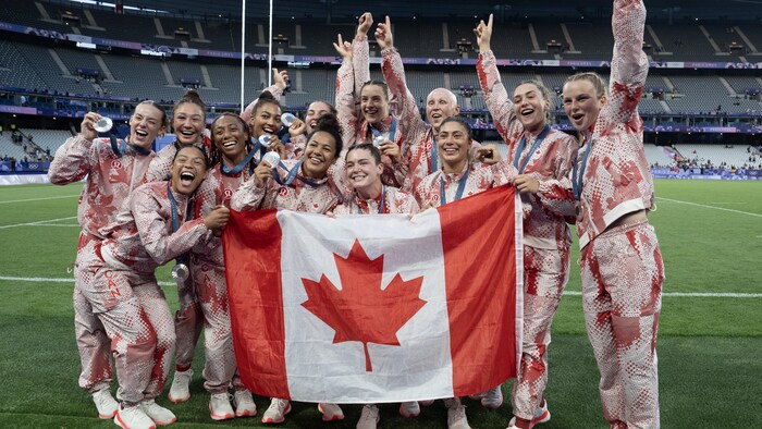 Les joueuses prennent une photo avec le drapeau canadien. 