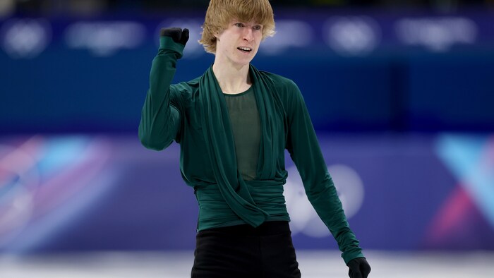 Stephen Gogolev le poing en l'air à la fin de sa prestation au programme libre de patinage artistique aux Jeux olympiques de Milan-Cortina. 