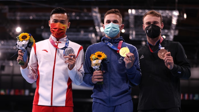 Trois athlètes avec des masques sanitaires montrent leurs médailles.
