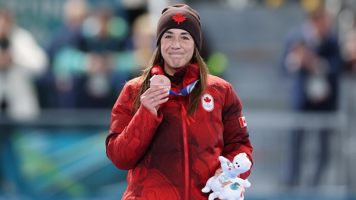 Elle tient sa médaille en souriant.
