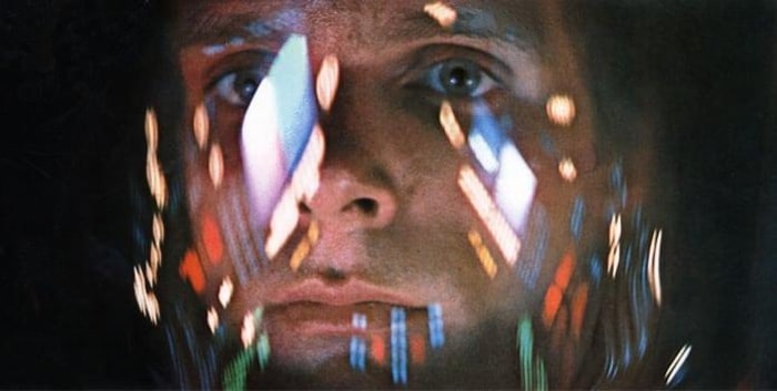 Still from a movie featuring an astronaut with lights reflecting against the glass of his helmet.