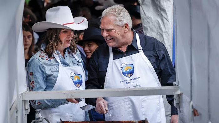 Danielle Smith et Doug Ford préparant des crêpes lors du petit déjeuner annuel du Stampede à Calgary, le 7 juillet.