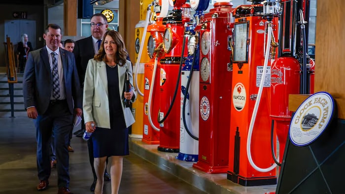 La première ministre de l'Alberta, Danielle Smith, à droite, passe devant des pompes à essence anciennes pour annoncer une nouvelle mesure visant à améliorer l'accessibilité financière à Calgary, le 17 juin.
