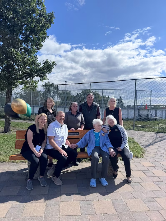 Un groupe de personnes sont assises sur un banc dans le quartier de Rosslyn, à Edmonton.