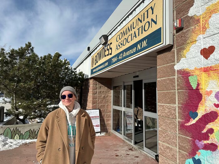 Une personne se tient devant une enseigne d'une association communautaire, à Calgary, 2026.