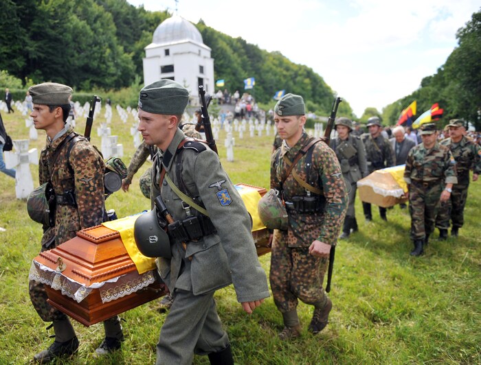 Des hommes en uniforme militaire transportent des cercueils.