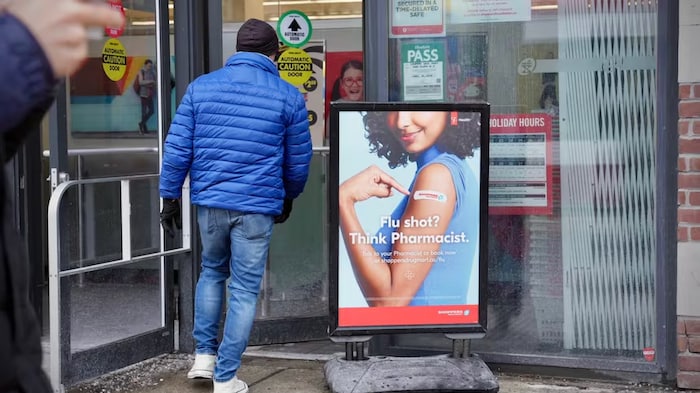 Un homme passe devant une affiche de campagne pour la vaccination contre la grippe.