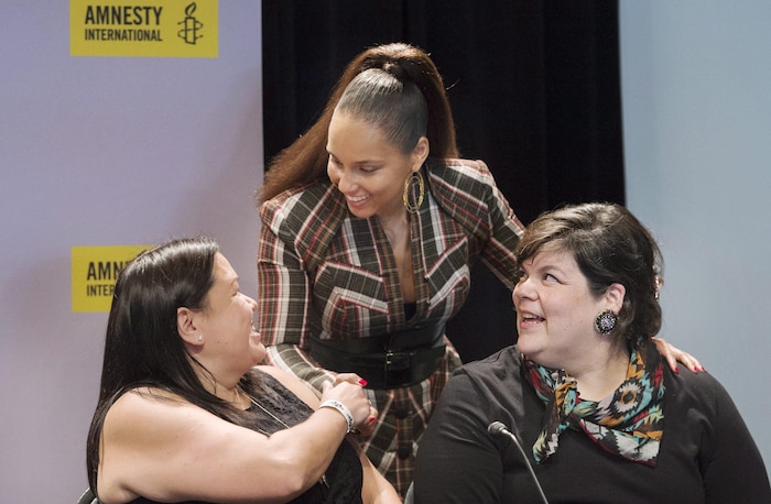 La chanteuse Alicia Keys serre la main à la militante autochtone Melanie Morrison, sous le regard d'une autre militante, Melissa Mollen Dupuis.