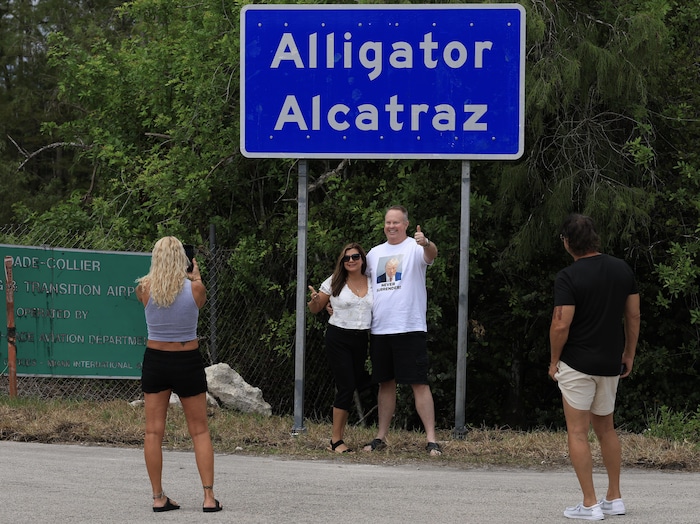 Des gens posent devant un panneau