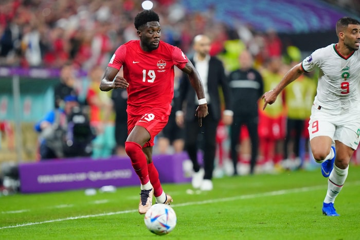 En contrôle du ballon, Alphonso Davies court en regardant vers sa gauche.