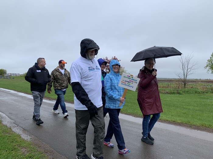 Six personnes marchent sous la pluie
