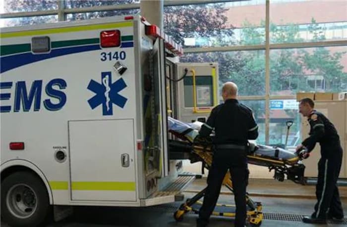 Deux ambulanciers paramédicaux poussent une civière par la porte arrière d'une ambulance.
